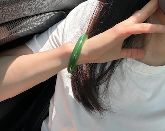 May include: A green jade bangle bracelet. The bracelet is smooth and polished.