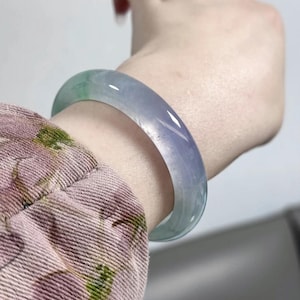 Könnte beinhalten: Ein hellgrünes und lavendelfarbenes Jade-Armband. Das Armband ist glatt und poliert.