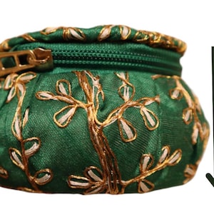 May include: A small green zippered pouch with gold embroidery of leaves and branches. The pouch is 3 inches tall.
