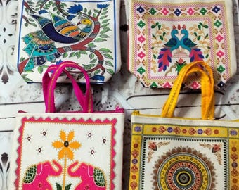 May include: Four colorful tote bags with patterned designs. One bag features a peacock, another has two peacocks, a third displays pink elephants, and the last has a circular design. Each bag has a different color handle.