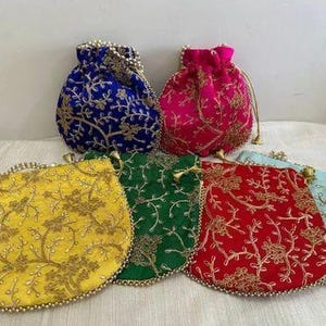 Puede incluir: Una colección de seis bolsas con cordón bordadas en varios colores: azul, rosa, amarillo, verde, rojo y azul claro. Cada bolsa presenta intrincados bordados florales dorados y ribetes de cuentas.