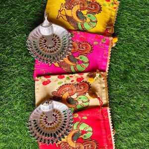 May include: Four colorful fabric pouches with peacock designs and a silver-toned decorative fan. The pouches are yellow, pink, beige, and red, each featuring a detailed peacock illustration. The fan has an intricate, openwork design.