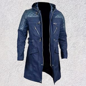 May include: A navy blue hooded coat with quilted shoulder panels. The coat has multiple pockets, zippers, and toggle fastenings. The coat is open, revealing a black interior.
