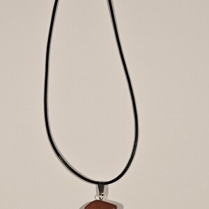 May include: A brown stone pendant on a black cord necklace.