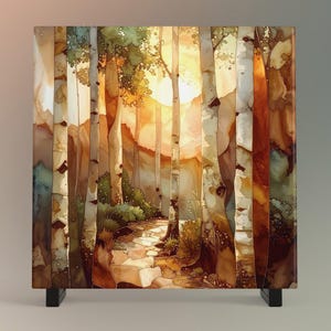 May include: A square decorative panel featuring a watercolor painting of a forest scene. The artwork depicts tall, slender trees with white and brown bark, a stone path, and a warm, golden sunset. The panel is supported by two black legs.