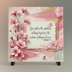 May include: A square canvas print featuring a floral design with pink cherry blossoms and the text "Now faith is the substance of things hoped for. the evidence of things not seen. Hebrews 11:1". The background has pink brushstrokes and gold accents.