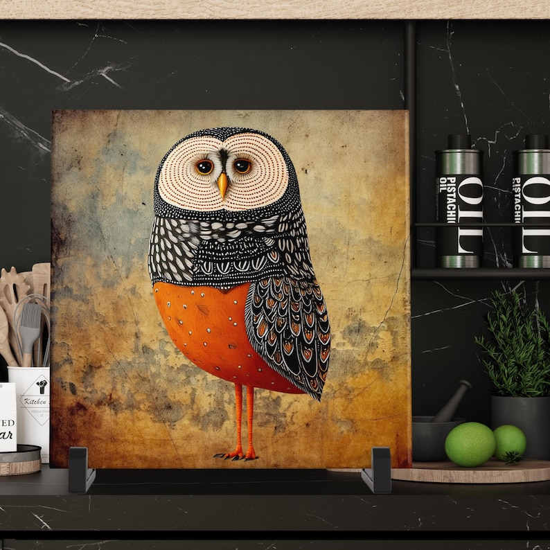 May include: A square decorative panel featuring a stylized owl illustration. The owl has a cream-colored face, black and white patterned wings, and an orange body. The background is a textured, sepia-toned design.