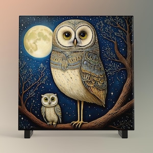 May include: A painting of two owls perched on a branch under a full moon. The larger owl is white with brown and gold markings, while the smaller owl is brown with white markings. The background is a dark blue with stars.