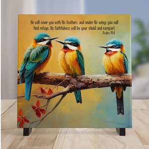 May include: A square canvas print featuring three colorful birds perched on a branch. The birds have blue, green, yellow, and orange feathers. The print includes the text "He will cover you with His feathers...Psalm 91:4."