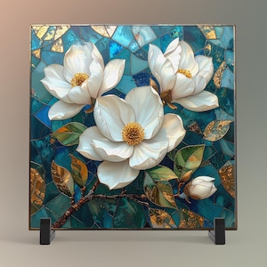 May include: A square mosaic art piece featuring white magnolia flowers with yellow centers against a teal and gold background. The artwork is displayed on a black stand, showcasing the floral design.