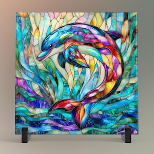 May include: A colorful stained glass panel featuring a dolphin leaping through water. The dolphin is depicted in shades of blue, red, yellow, and purple. The panel is square and mounted on a black stand. The artwork is reminiscent of a mosaic.