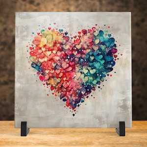 May include: A colorful heart made of many smaller hearts in shades of red, pink, blue, yellow, and green. The heart is on a gray background.