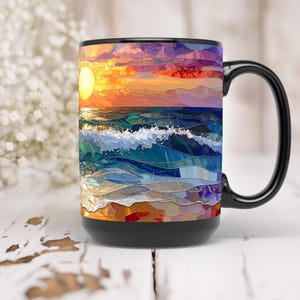 May include: Black coffee mug featuring a vibrant mosaic design of a sunset over the ocean. The artwork includes a bright yellow sun, orange and purple sky, and blue and white waves. The mug has a black handle and base.