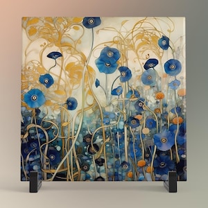 May include: A square glass tile with a floral design featuring blue flowers and gold stems on a white background. The tile is mounted on a black metal stand.