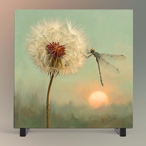 May include: A square canvas print featuring a detailed dandelion seed head with a white, fluffy globe and a brown center. A blue-green dragonfly with translucent wings is perched on the side. The background shows a soft, hazy sunset over a field.