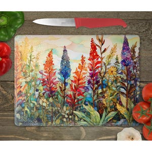 May include: A colorful glass cutting board with a watercolor design of tall flowers in shades of red, blue, yellow, and green. The flowers are arranged in a field with a hazy background.