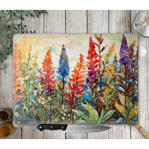 May include: A colorful watercolor painting of a field of flowers. The flowers are in shades of red, orange, yellow, blue, and purple. The background is a soft, hazy blue.