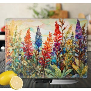 May include: A colorful glass cutting board with a watercolor-style floral design. The design features a variety of flowers in shades of red, blue, yellow, and green. The flowers are arranged in a cluster, with the tallest flowers in the center of the design. The background of the design is a light blue watercolor wash.