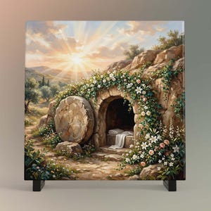 May include: A square canvas print depicts an open tomb with a large stone rolled away. The scene is illuminated by a bright sunburst, with a stone archway covered in flowers. The artwork evokes a sense of peace and renewal.
