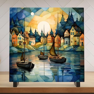 May include: A watercolor painting of a small town with sailboats on a lake. The town is made up of colorful houses with white trim. The sailboats are black and have white sails. The lake is a deep blue color and the sky is a light blue with white clouds. The sun is setting in the background, casting a warm glow over the scene.