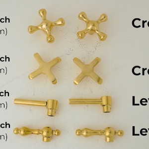 May include: Gold-toned metal cabinet knobs in four different styles: cross, cross 2, lever, and lever 2. The knobs are shown in various sizes, ranging from 2.75 inches (70 mm) to 3.54 inches (90 mm).