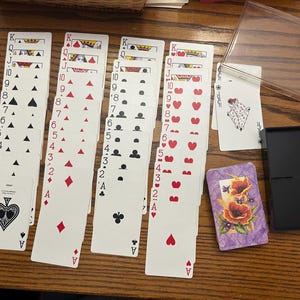 Jeu de cartes avec fleurs ( un paquet orange avec fleurs et un paquet violet avec fleurs) dans un étui en plastique
