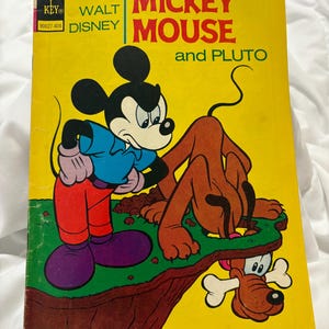 May include: A vintage comic book cover featuring Mickey Mouse and Pluto. The cover is yellow with a red and blue illustration of Mickey Mouse and Pluto. The title reads "Mickey Mouse and Pluto" with the text "Walt Disney" and "Gold Key" in the top left corner.