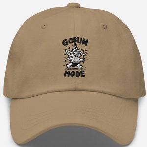 May include: A tan baseball cap with the words "GOBLIN MODE" embroidered in black. The design includes a cartoon goblin character with a party hat and a wand.