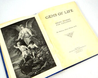 Może przedstawiać: Otwarta książka zatytułowana "Gems of Life: Short Stories for Children" autorstwa Biskupa Almy White, A.M. Okładka książki przedstawia czarno-białą ilustrację anioła z dwojgiem dzieci.