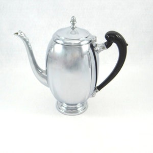 May include: A silver teapot with a black handle. The teapot has a rounded body and a shiny finish.