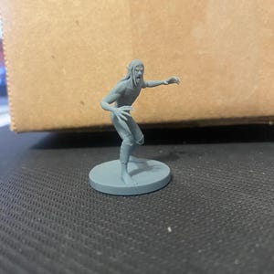 May include: A gray plastic miniature figurine of a humanoid creature with pointed ears, a snarling expression, and clawed hands. The figurine is standing on a round base.