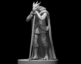 May include: A gray painted miniature figurine of a dragon-like humanoid figure wearing a cloak and holding a staff. The figure is standing on a round base.