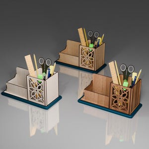 May include: Three wooden desk organizers with a cutout design. Each organizer has a compartment for pens and pencils, a slot for a ruler, and a small tray for paper clips or other small items. The organizers are made of light brown wood and have a dark blue base.