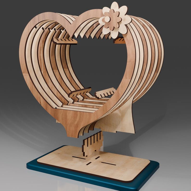 May include: A wooden heart-shaped sculpture with intricate layers and a small flower on top. The sculpture is mounted on a wooden base with a teal blue border.