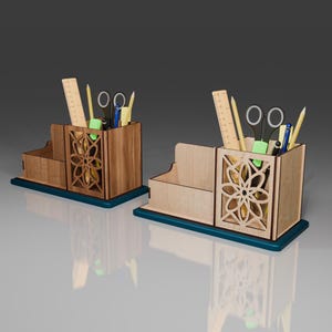 May include: Two wooden desk organizers with a teal base. Each organizer has a compartment for pens and pencils, a small drawer, and a decorative cutout design. The organizers are filled with various office supplies, including rulers, scissors, and pens.