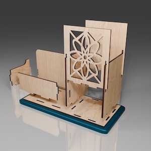 May include: A wooden desk organizer with a decorative cutout design. The organizer has a teal base and a compartment with a floral pattern.