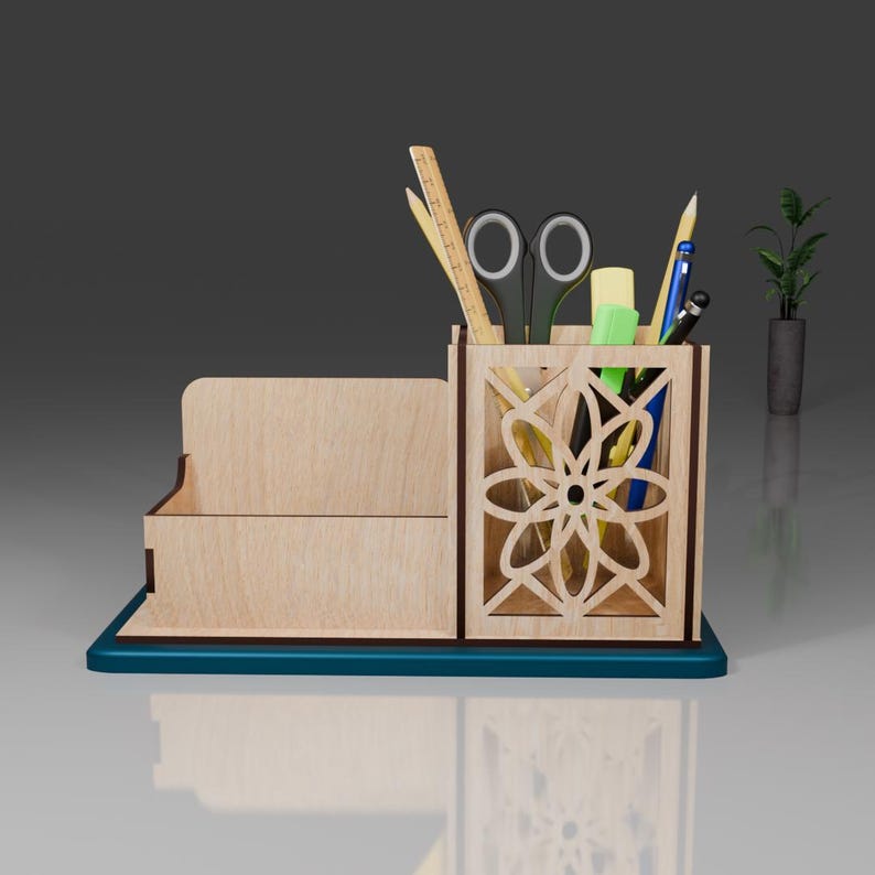 May include: Wooden desk organizer with a cutout design in the shape of a flower. The organizer has a compartment for pens and pencils, a slot for a ruler, and a small tray for other items. The organizer is made of light brown wood and has a dark blue base.