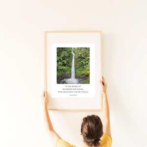 Op de afbeelding: Een ingelijste print met een foto van een waterval in een weelderig groen bos. De print bevat de quote "Te midden van beweging en chaos, bewaar de stilte in jezelf." - onbekend