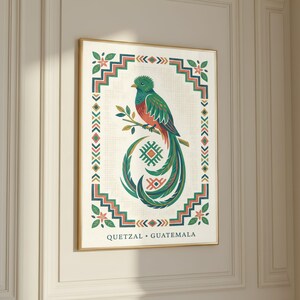 a framed illustration of a colorful bird, likely a quetzal, perched on a branch. The bird is surrounded by a decorative border with geometric patterns and designs. The text "QUetzal - Guatemala" is visible, indicating the bird is a quetzal from Guatemala.
