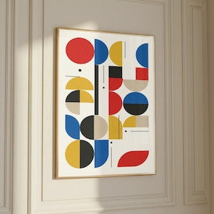 May include: A framed abstract art print featuring a geometric design. The artwork uses a palette of red, blue, yellow, black, and beige shapes, including circles, semi-circles, and rectangles, against a white background. The frame is a thin, gold color.