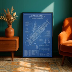 May include: A framed blueprint of a U.S. Naval attack submarine. The schematic is in white on a blue background, with detailed diagrams and text. The frame is black. The print is displayed in a room with an orange chair and a wooden side table.