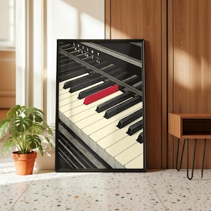 May include: A framed art print featuring a piano keyboard with black and ivory keys. One key is highlighted in red. The print has the text "LRYING TO CA" in the upper left corner. The artwork is displayed against a wooden wall.