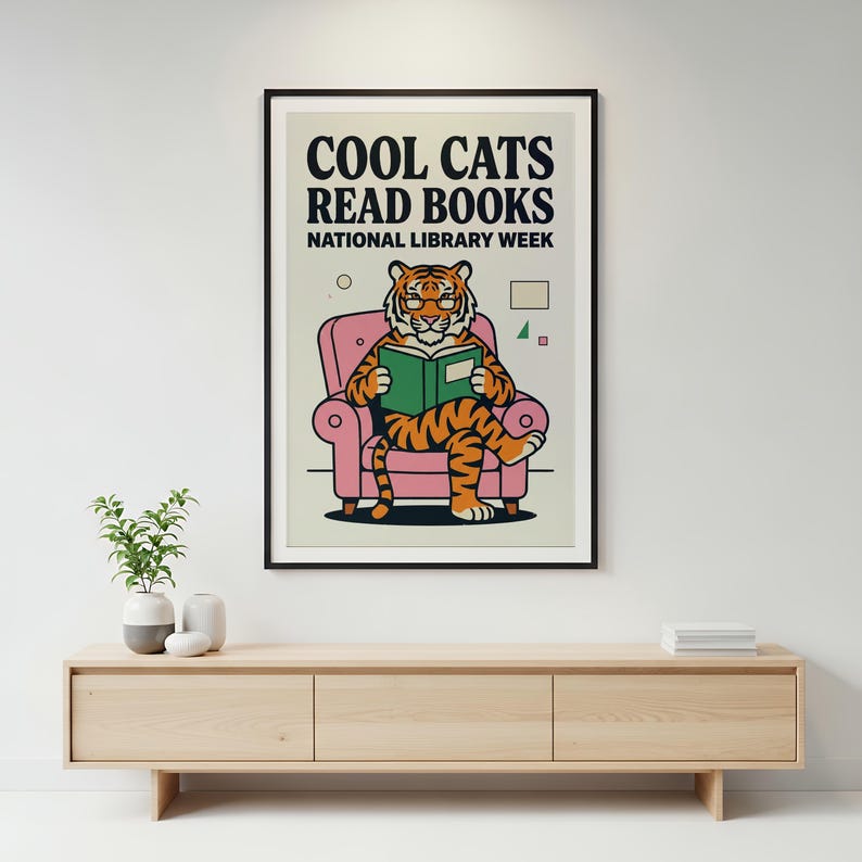 A poster with a tiger sitting in a pink chair and reading a book, mounted on a wall above a wooden cabinet.