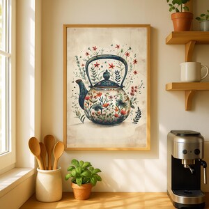 Op de afbeelding: Een ingelijste aquarelprint van een theepot met een bloemmotief in een keukenomgeving. De theepot is blauw en wit met rode en oranje bloemen. De print zit in een houten lijst. Houten lepels zitten in een witte keramische houder. Een kleine plant staat in een terracotta pot.