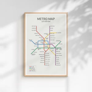 以下が含まれることがあります： メトロマップシティエディションのフレーム入りプリント。地図には、地下鉄の路線を表す色の付いた線のネットワークがあり、駅名が黒で表示されています。プリントは木製のフレームに入っています。