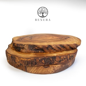 May include: Three rustic, wooden serving boards stacked on top of each other. The boards are oval-shaped with natural edges and a light brown color. The top board has a smooth surface, while the edges show the natural wood grain. The brand name "BENERA" is above the boards.