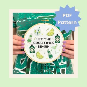 Könnte beinhalten: Ein Kreuzstich-Stickrahmen mit weißem Hintergrund und grüner und schwarzer Stickerei. Die Stickerei zeigt eine Gin-Flasche, eine Limettenscheibe, ein Martini-Glas und den Text "Let the good times be-gin".