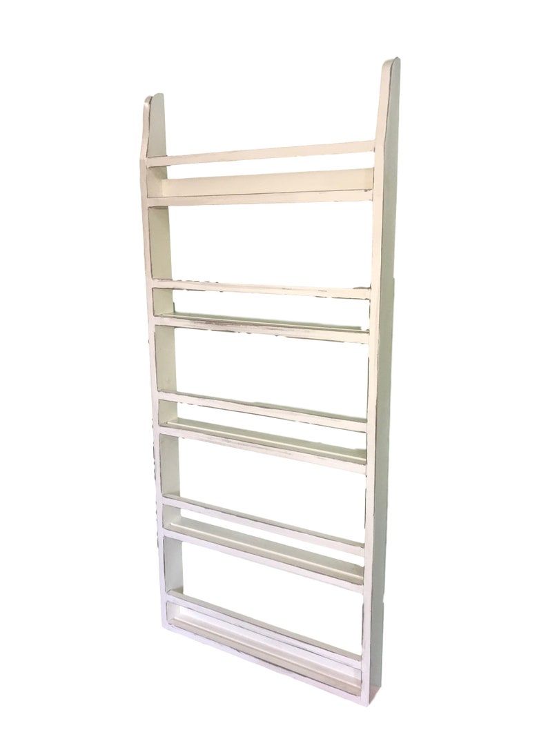 May include: White wooden wall mounted shelf with six shelves. The shelf is distressed and has a rustic look.