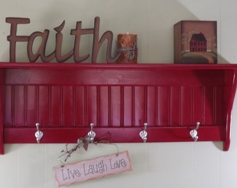 May include: Red wooden shelf with four hooks and a decorative sign that says "Live Laugh Love". The shelf has a slatted front and is decorated with the word "Faith" and a small house-shaped box.