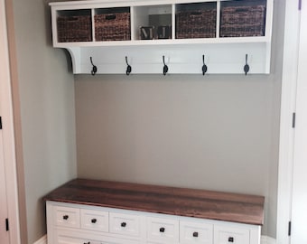 May include: White hallway bench with a wooden top and six drawers. The bench has a white shelf with three wicker baskets and hooks for hanging coats.